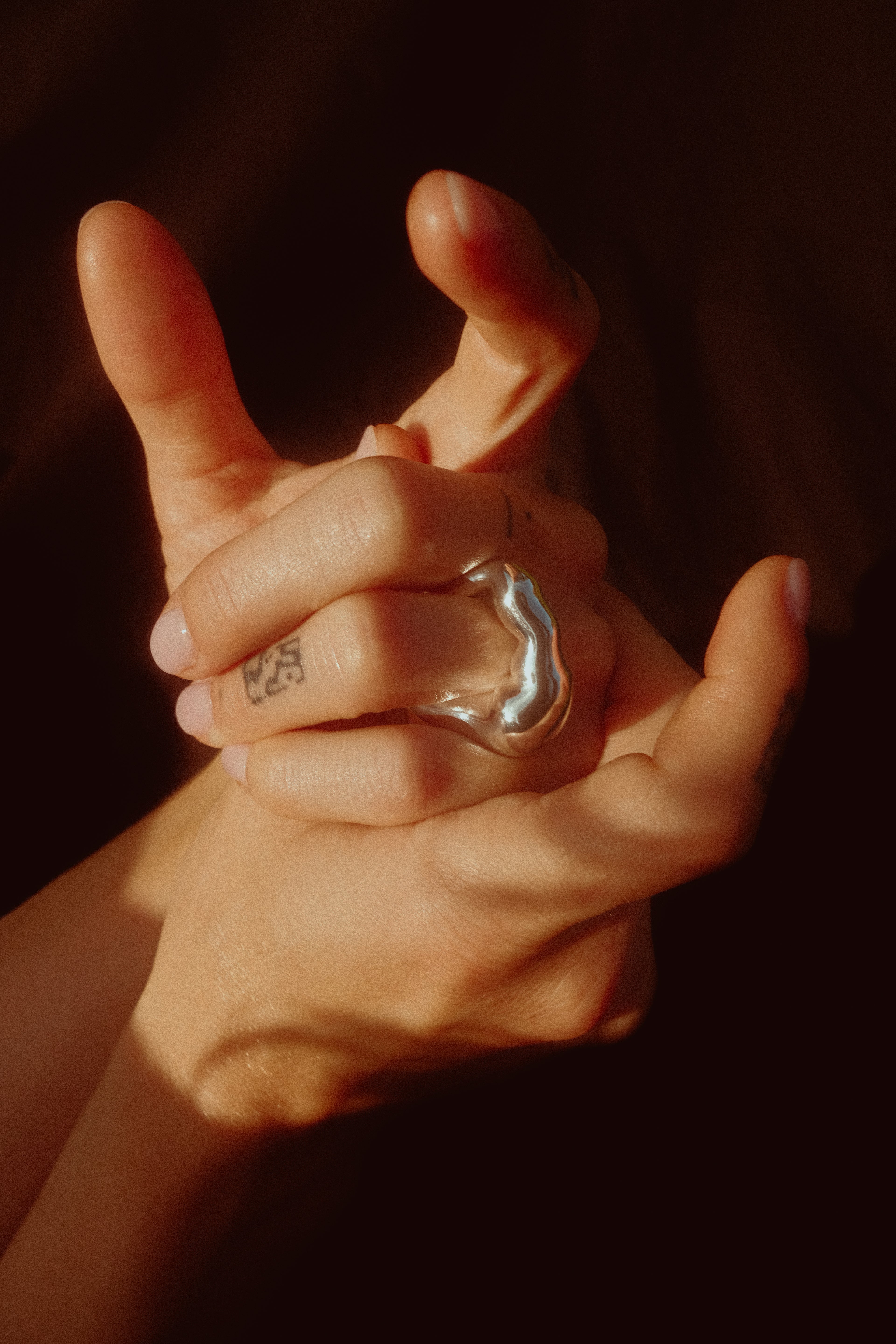 Close-up of two hands with rings on a dark background